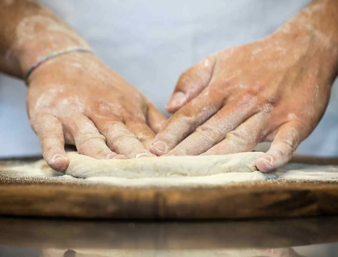 Opening the pizza dough with hands - 799x610