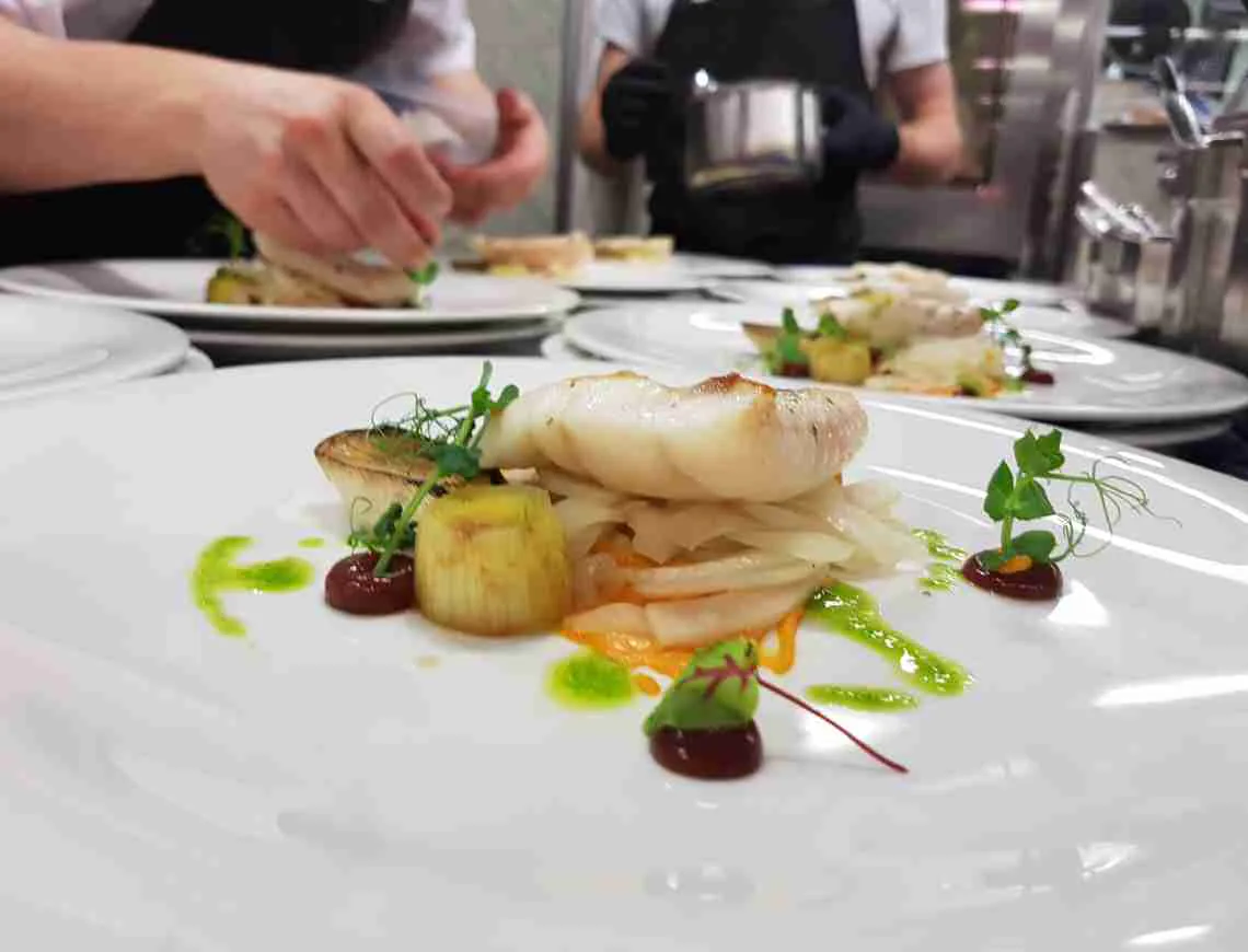 Chef plating a fish fillet - 799x610