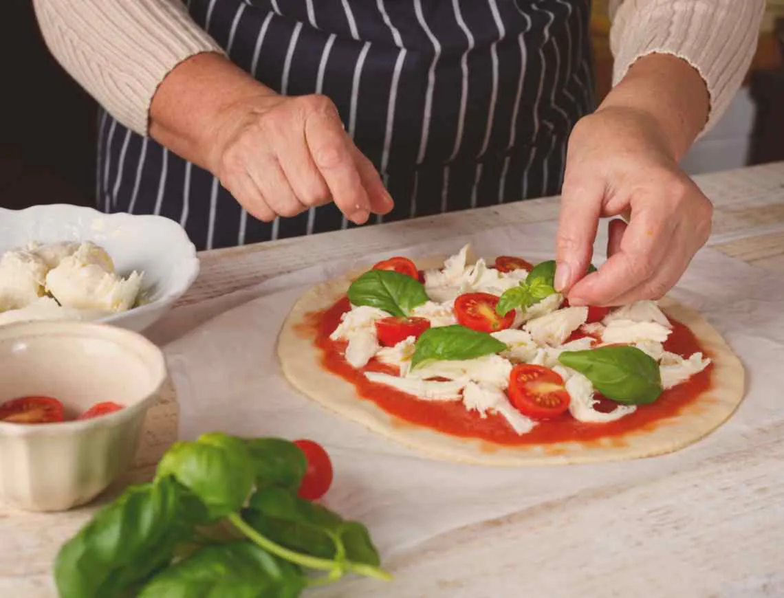 Finishing pizza making with fresh basil - 799x610