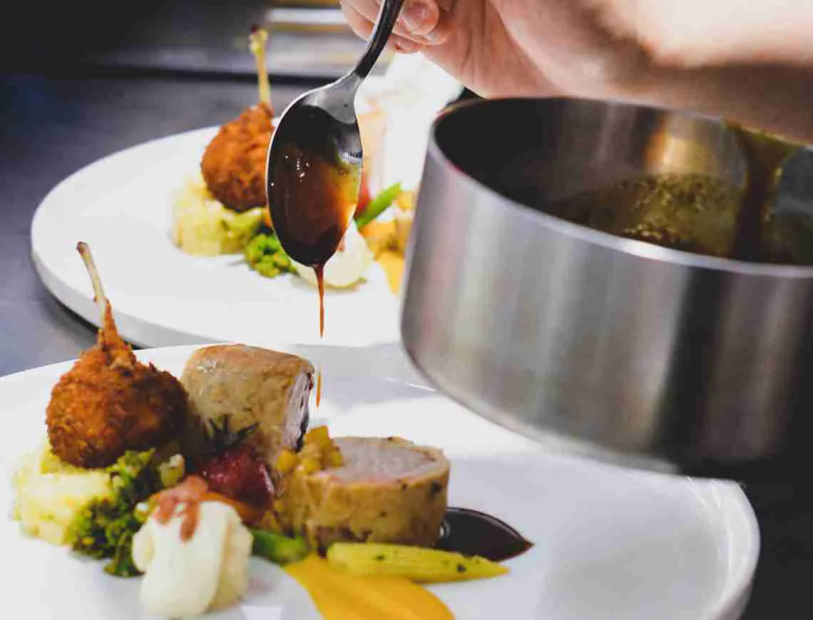 Chef putting glaze on lamb cutlets - 799x610