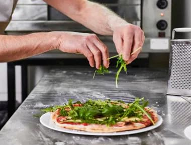 Person putting rocket on pizza