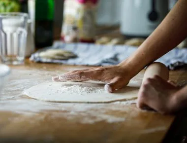 Person flatting the dough for pizza
