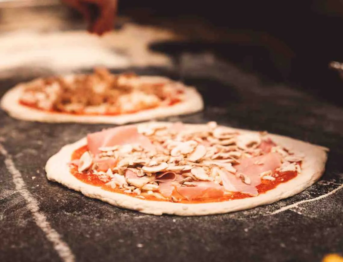 Pizza chef preparing a capricciosa pizza - 799x610